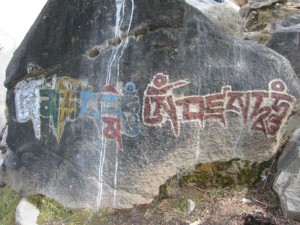 Il mantra Om Mani Padme Hum scritto in diversi colori su una roccia fuori dal Potala in Tibet, le lettere rosse sulla destra sono un altro mantra.