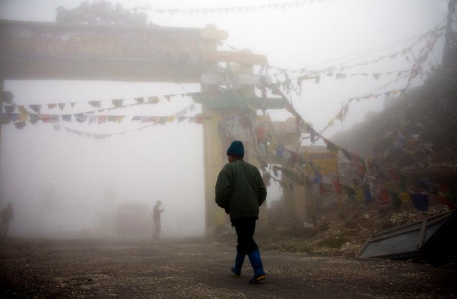 Bandiere di preghiera tibetane, simbolo d'armonia e di pace, sventolano nella nebbia del mattino al Sela Pass nella regione di Tawang dell'Aunachal ai confini del Tibet 