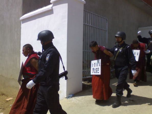 tib-burn6 Monaci con le mani legate dietro la schiena e con un cartello al collo col loro nome e le accuse di separatismo ed indipendentismo, espulsi dalla polizia dal loro monastero e condotti in carcere.
