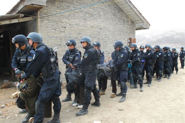 Prigionieri tibetani con le mani legate dietro la schiena costretti a piegarsi verso terra. 