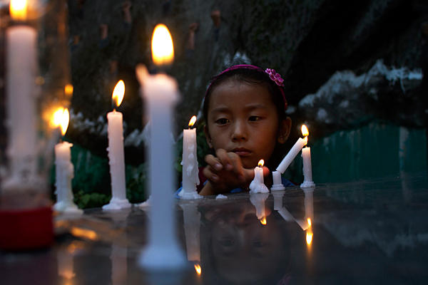 An exile Tibetan girl lights a candle during a candlelit vigil to remember two Tibetans who have self-immolated in Tibet, in Dharmsala, India, Tuesday, 7 August 2012