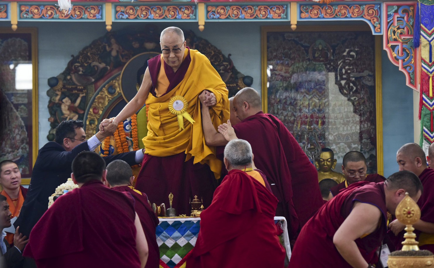 Tibetan spiritual leader the Dalai Lama is assisted by his aides as he prepares to perform rituals during the inauguration of a Mongolian Buddhist temple in Bodh Gaya, India, Jan. 9, 2017. (AP Photo/Manish Bhandari)
